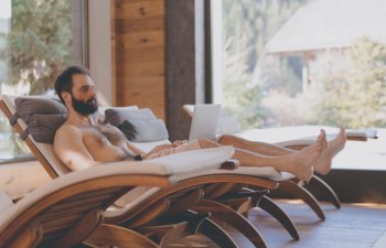 A middle-aged man with beard and moustache using his laptop while relaxing in a Spa armchair