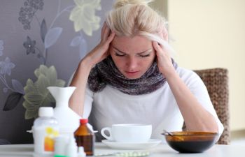 young woman fighting a cold symptoms sitting at the table with medications