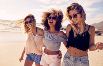 three energetic young women walking along the beach
