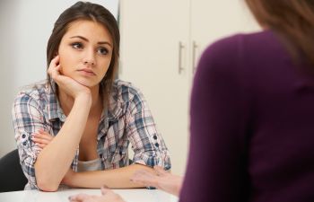 A depressed young woman at an appointment with a depression treatment specialist