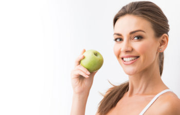 attractive woman holding an apple and smiling